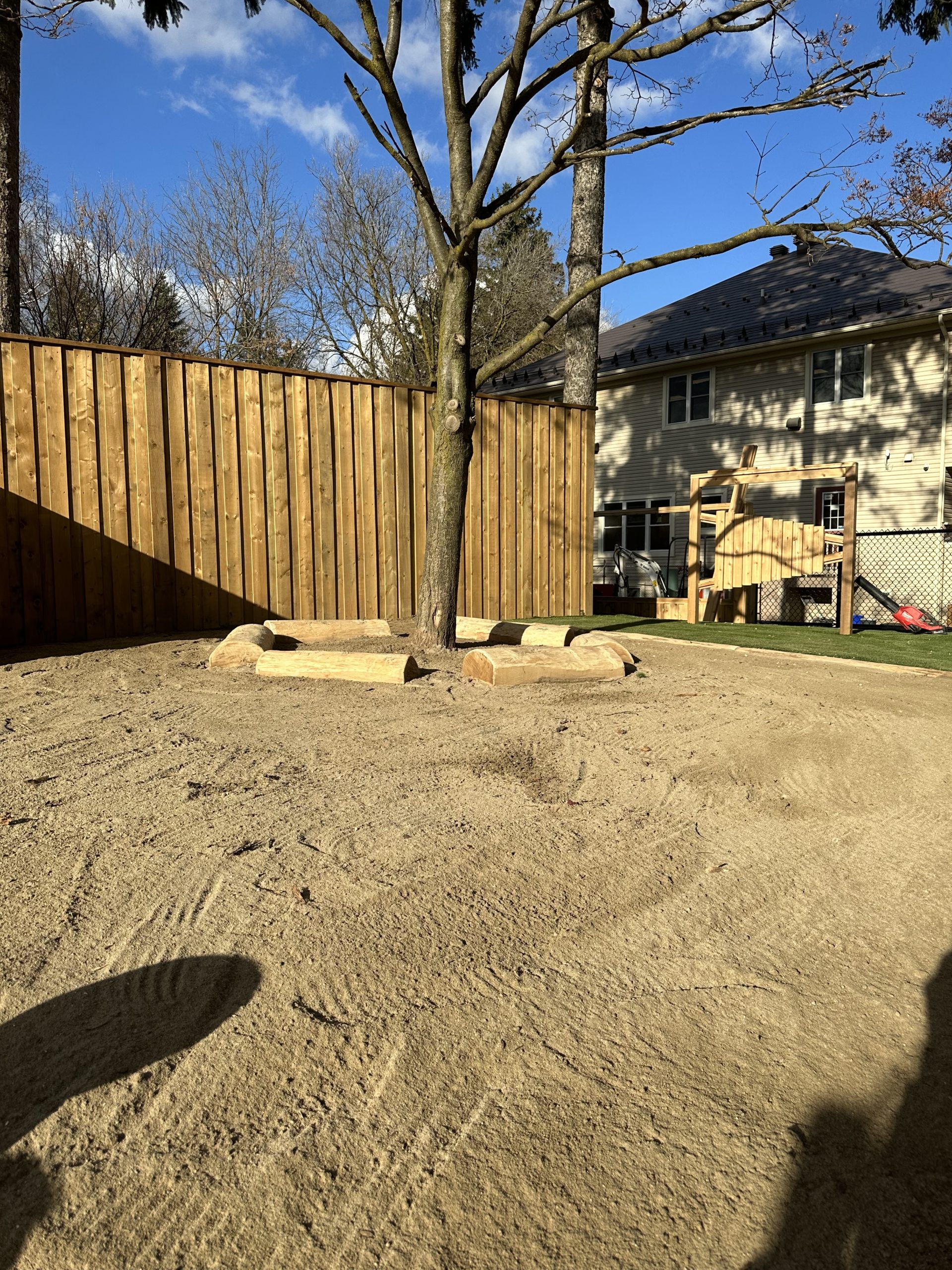 Natural play area with log stepping stumps, a wooden slide, and open turf