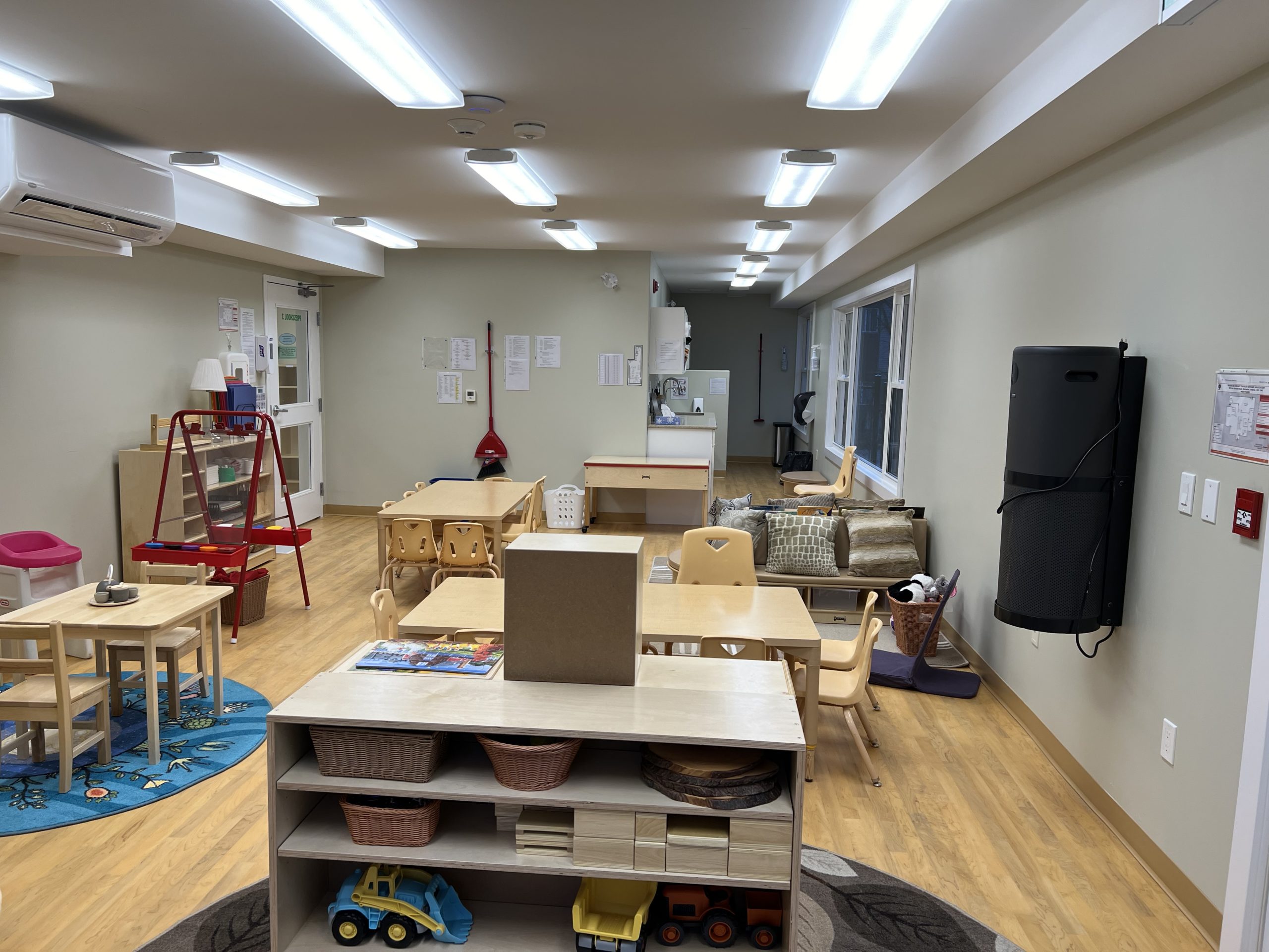 Toddler classroom with foldable rest mats, round rug, and toy shelving