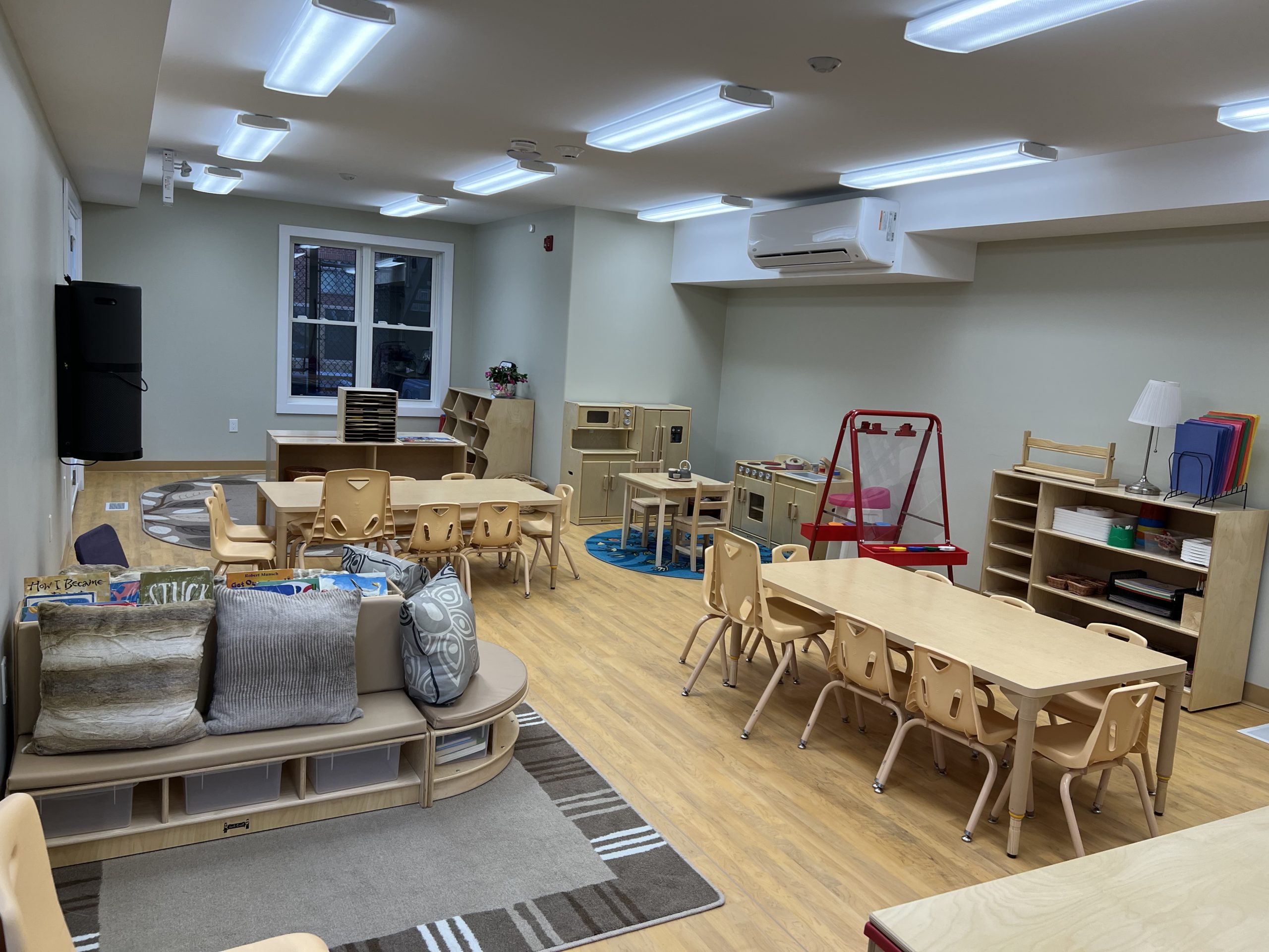 Wide view of preschool classroom with cushioned bench and shelving