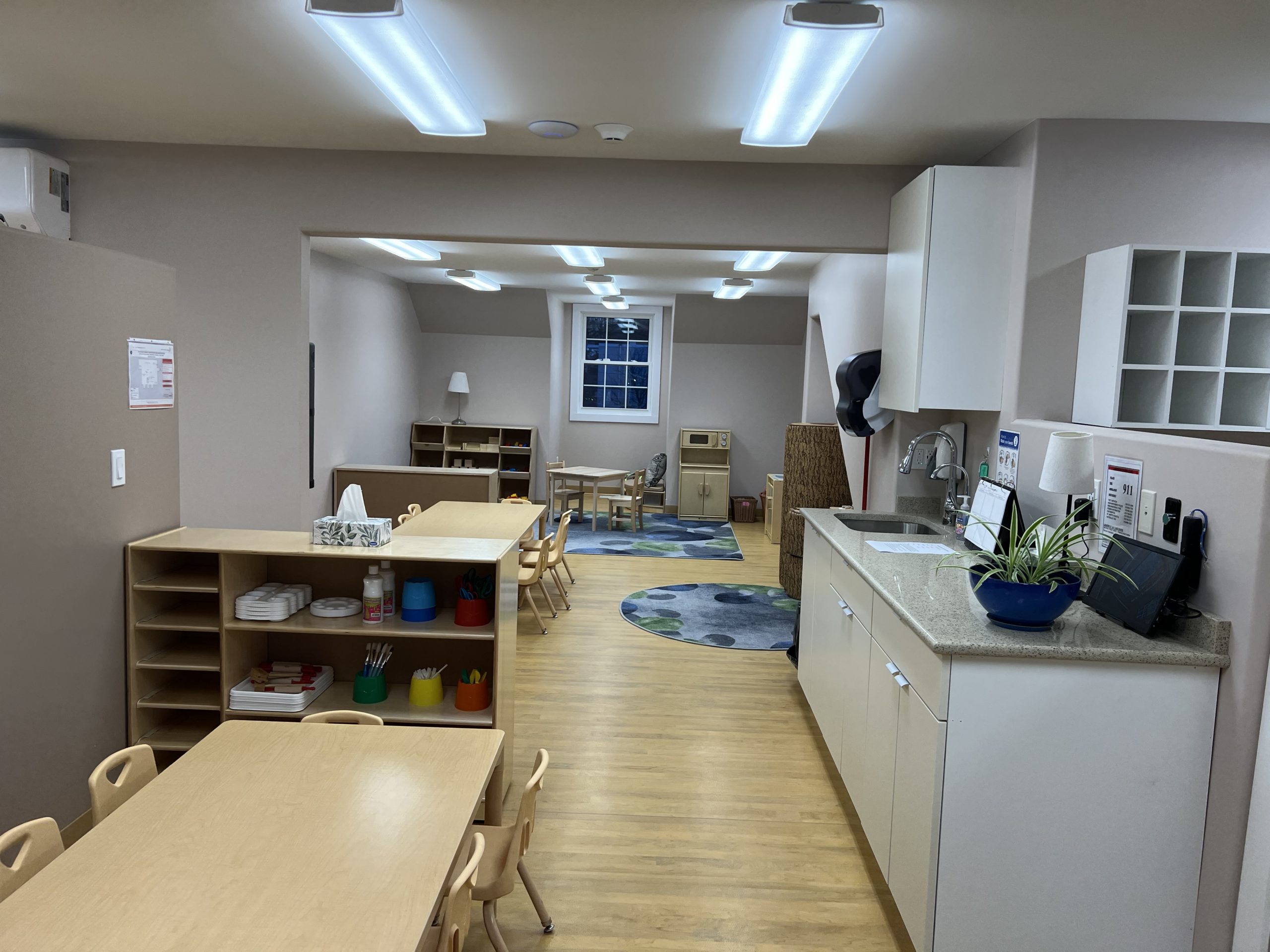 Attic-style classroom nook with open shelving, a small table, and a sink counter