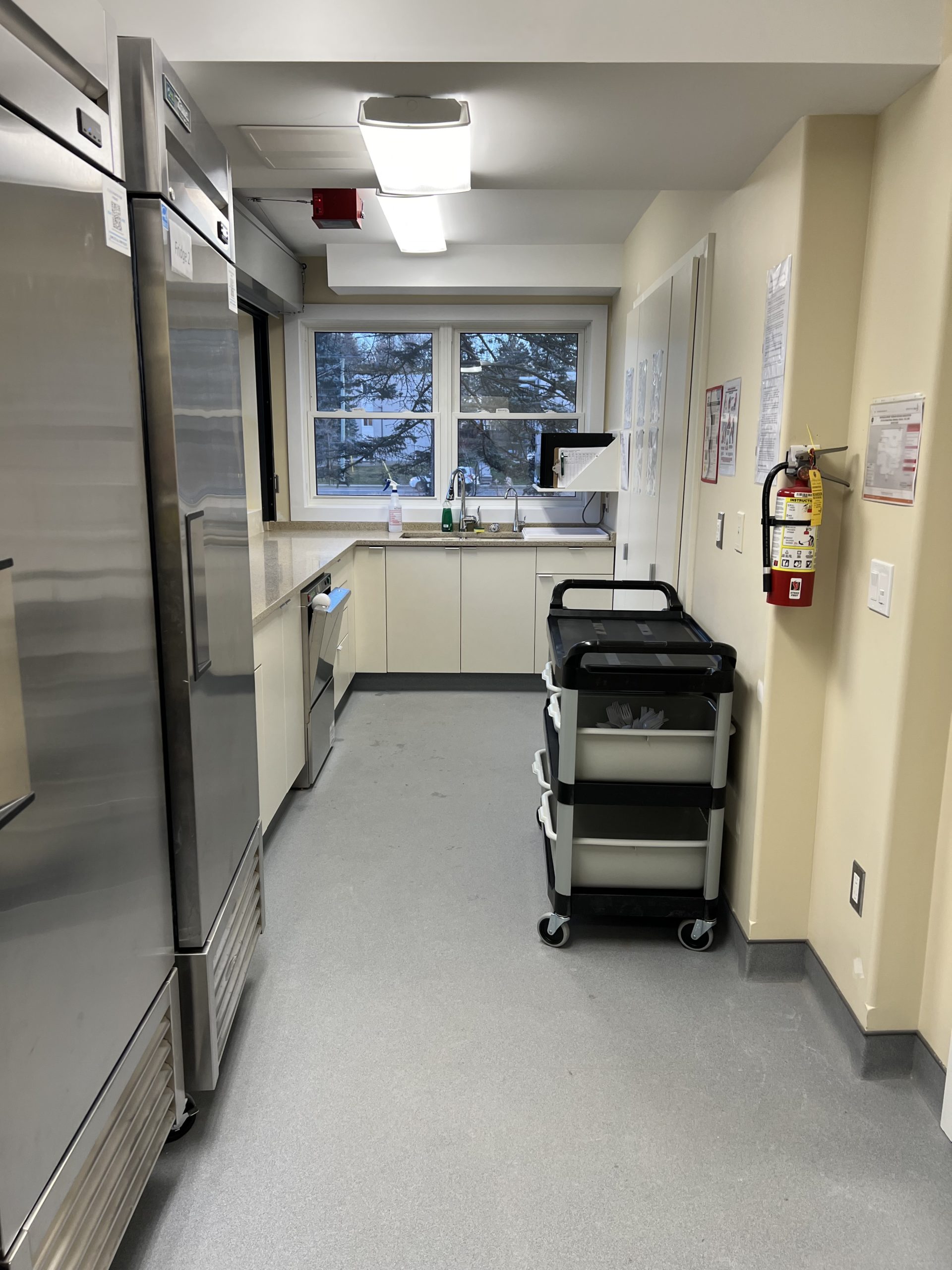 Kitchen prep area with stainless steel fridges, sink counter, and rolling cart