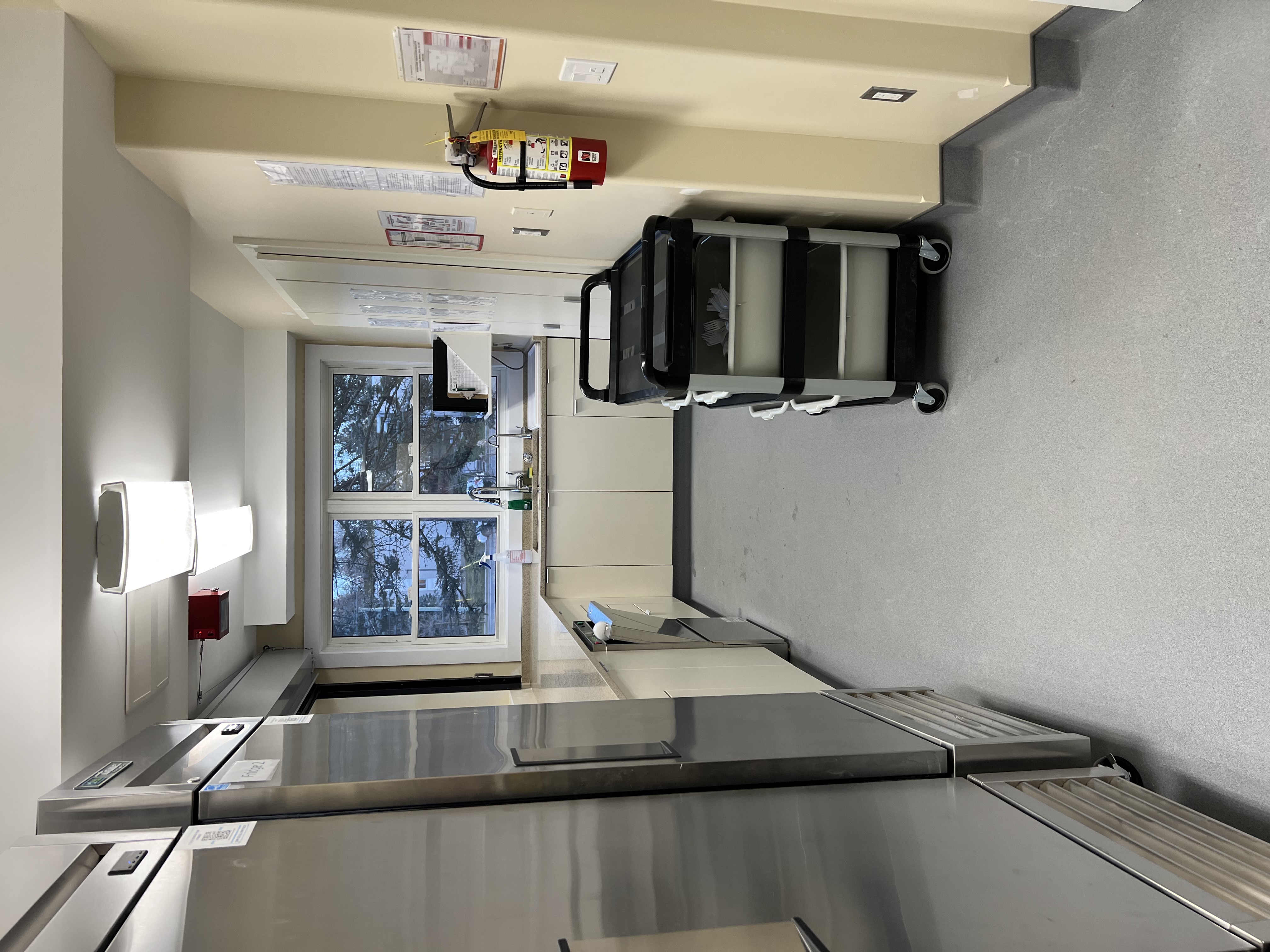 Bright kitchen with commercial appliances, sink, preparation counters, and storage cabinets