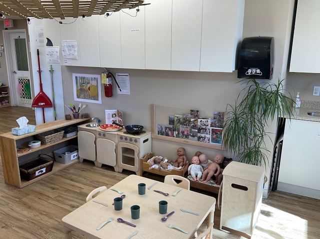 Pretend kitchen with baby dolls beside a table set for a meal