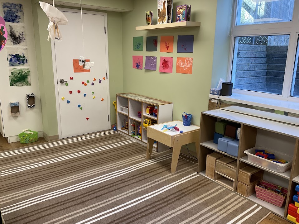 Open wooden toy shelving with blocks and puzzles beside a striped area rug