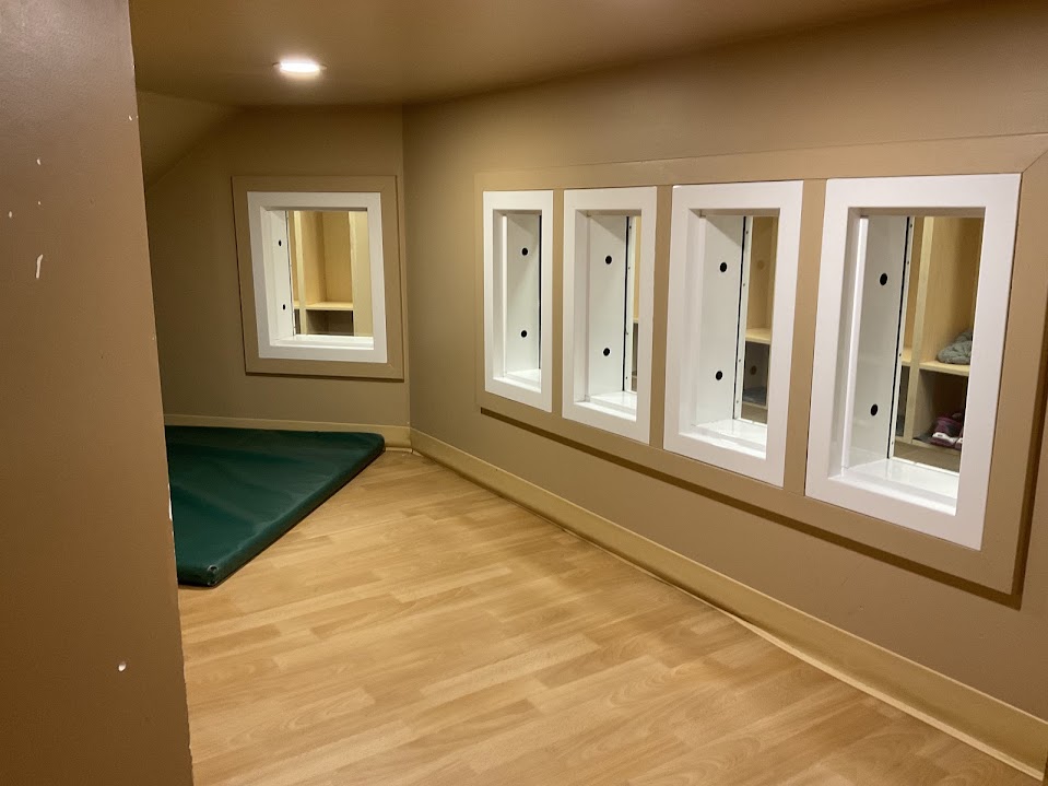 Adjoining room with framed wall cutouts and a green cushioned mat on the floor