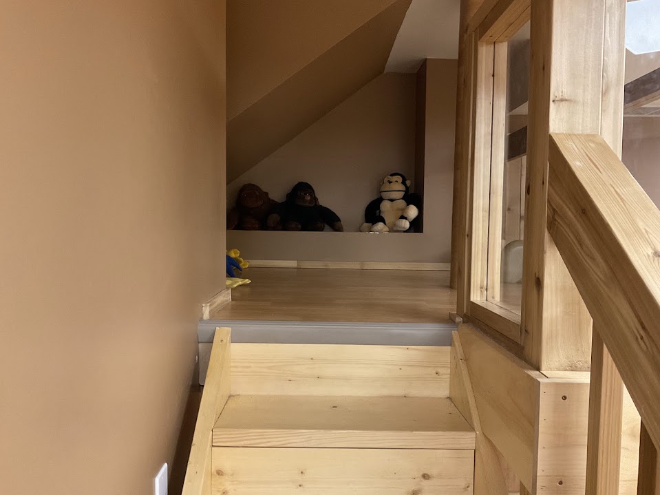 Cozy sloped-ceiling nook at the top of the stairs with stuffed monkey toys