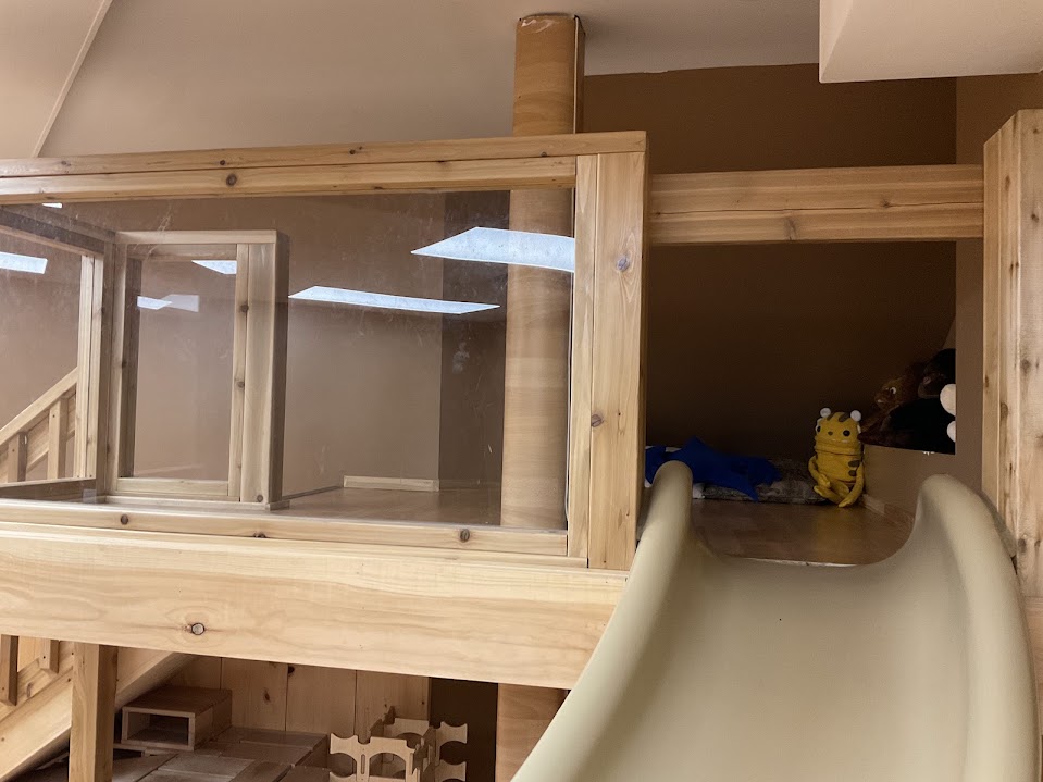 Close-up of the glass-walled lookout atop the loft, with a stuffed tiger toy at the top of the slide