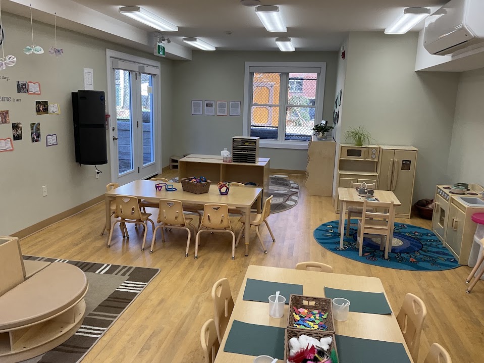 Preschool classroom with cushioned bench, low tables, and open shelving