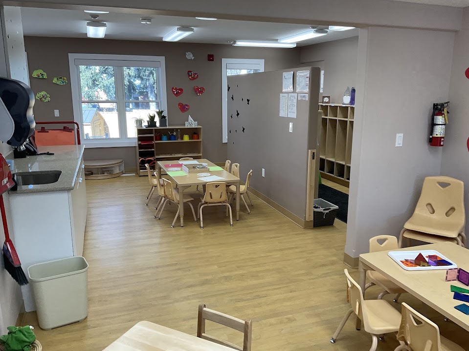 Classroom with group tables and cubby storage beneath a hearts-decorated wall