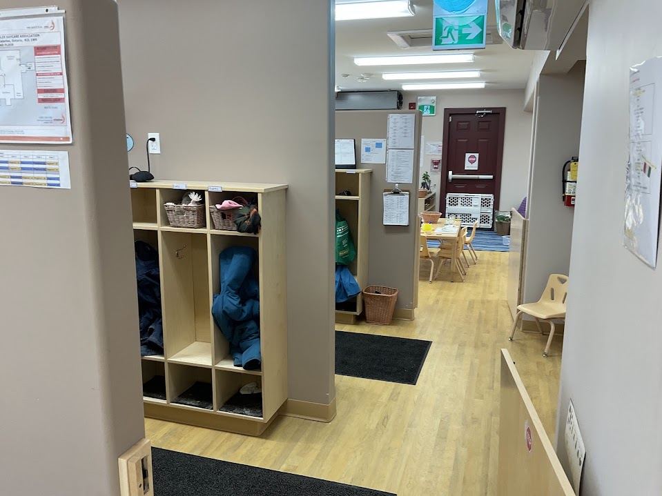 Hallway with children's cubbies and hooks leading into a classroom