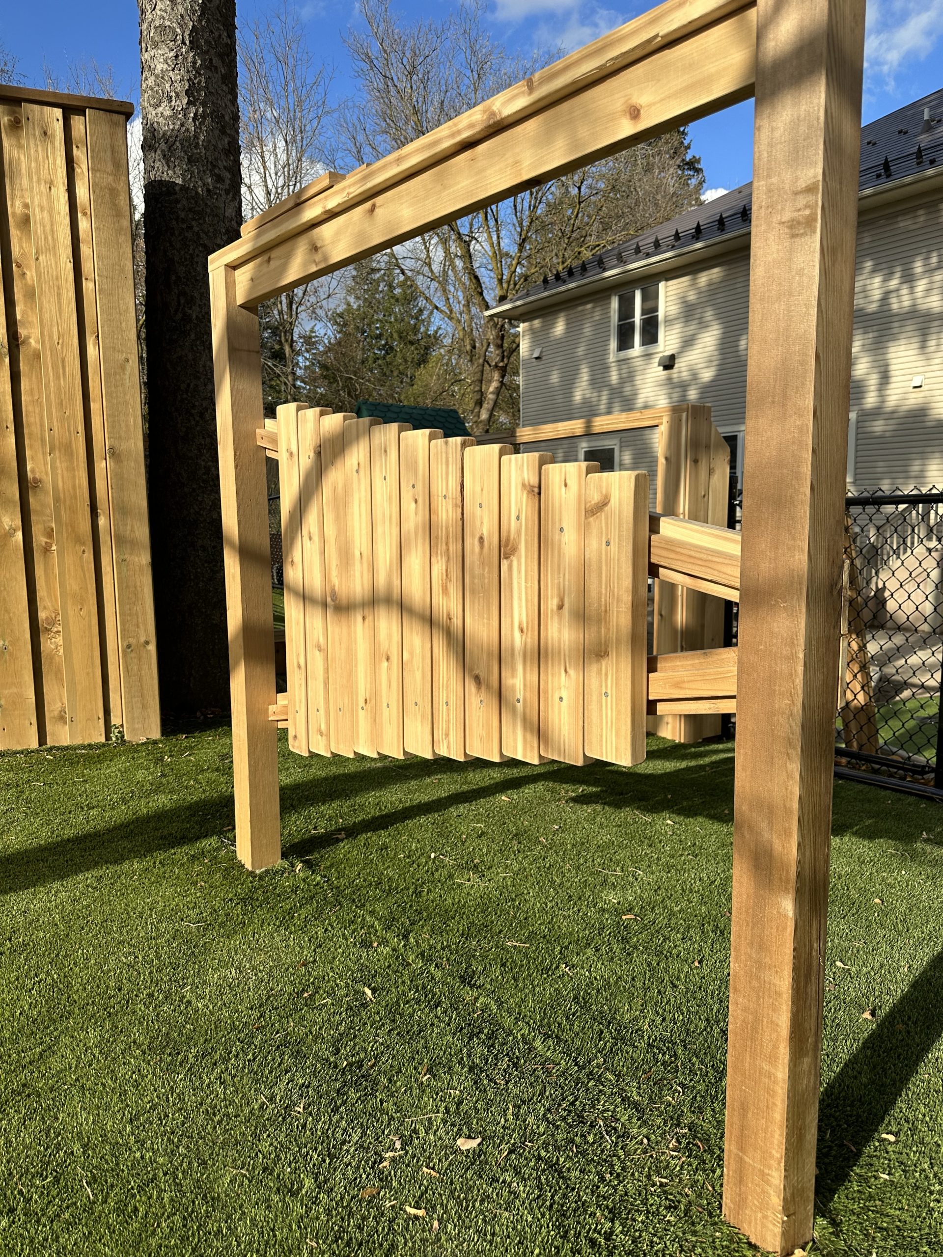 Wooden arbor with vertical cedar slat panel on the turf area