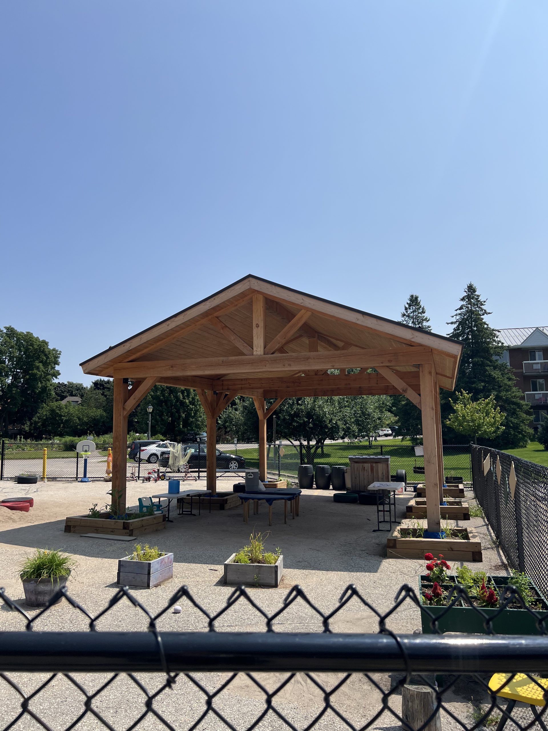 Large covered wooden pavilion with picnic tables and garden planters