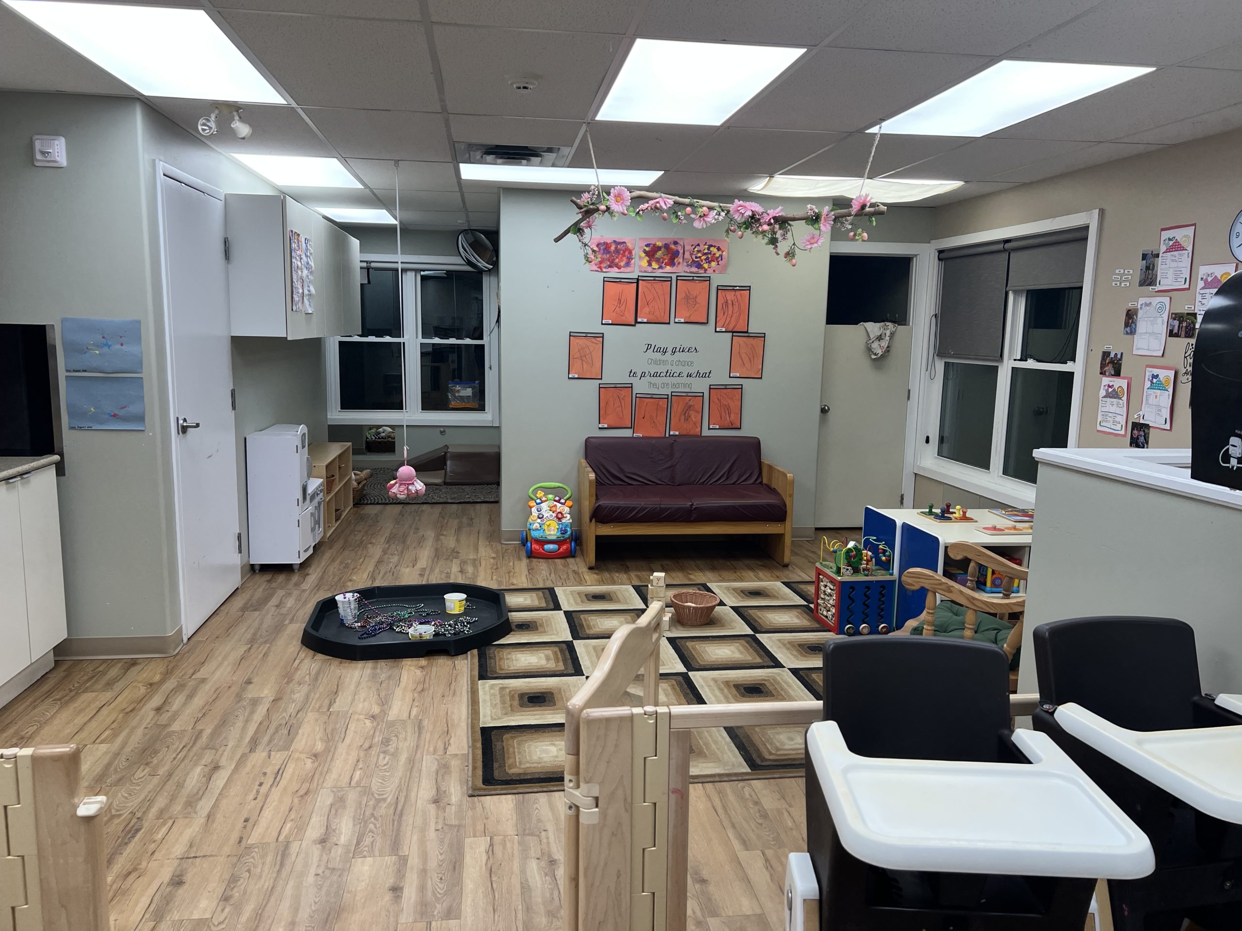 Play corner with a patterned rug, activity cube, wooden blocks and a rocking chair