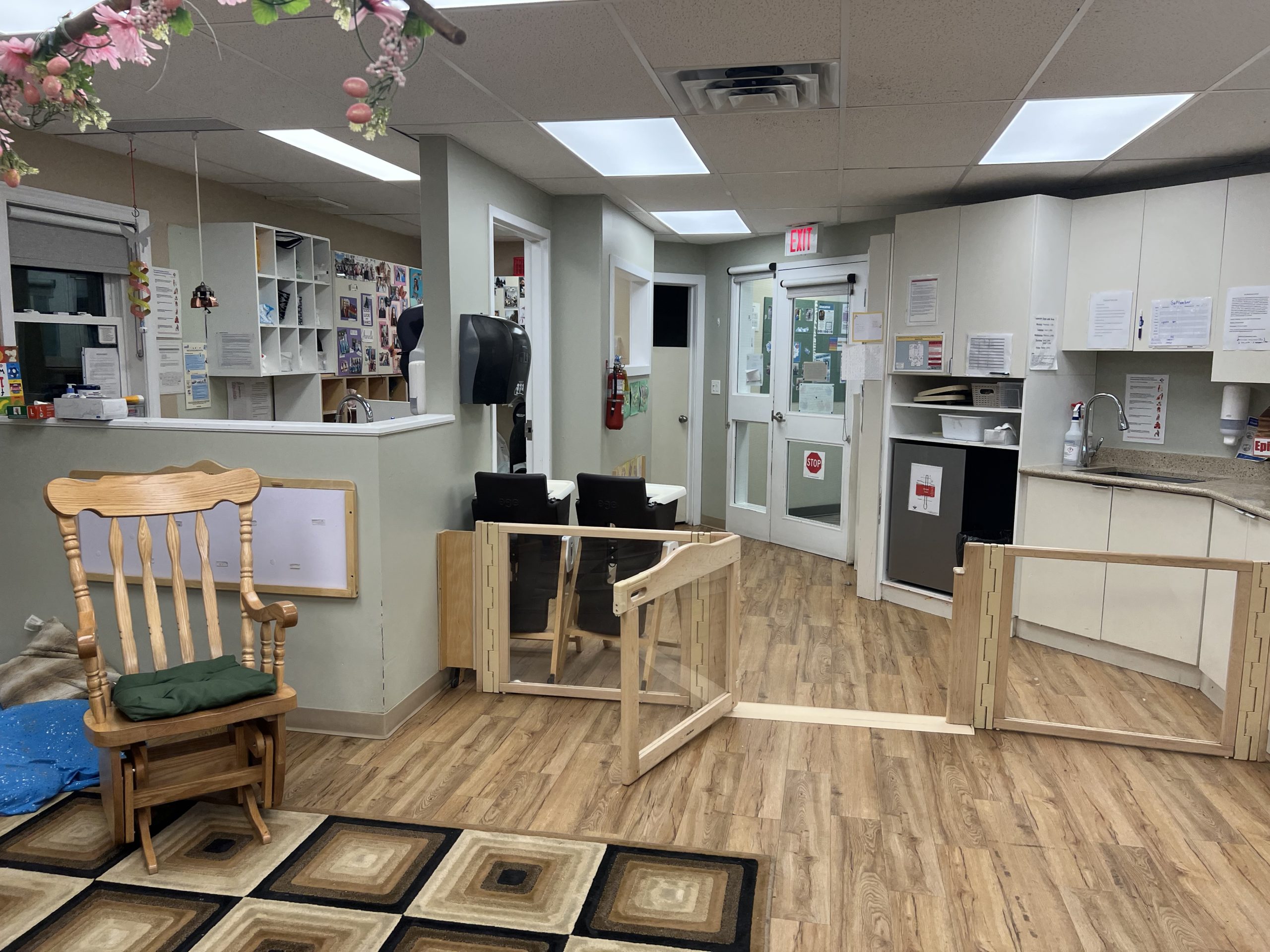 Infant room entrance with a wooden safety gate, kitchenette and cubbies