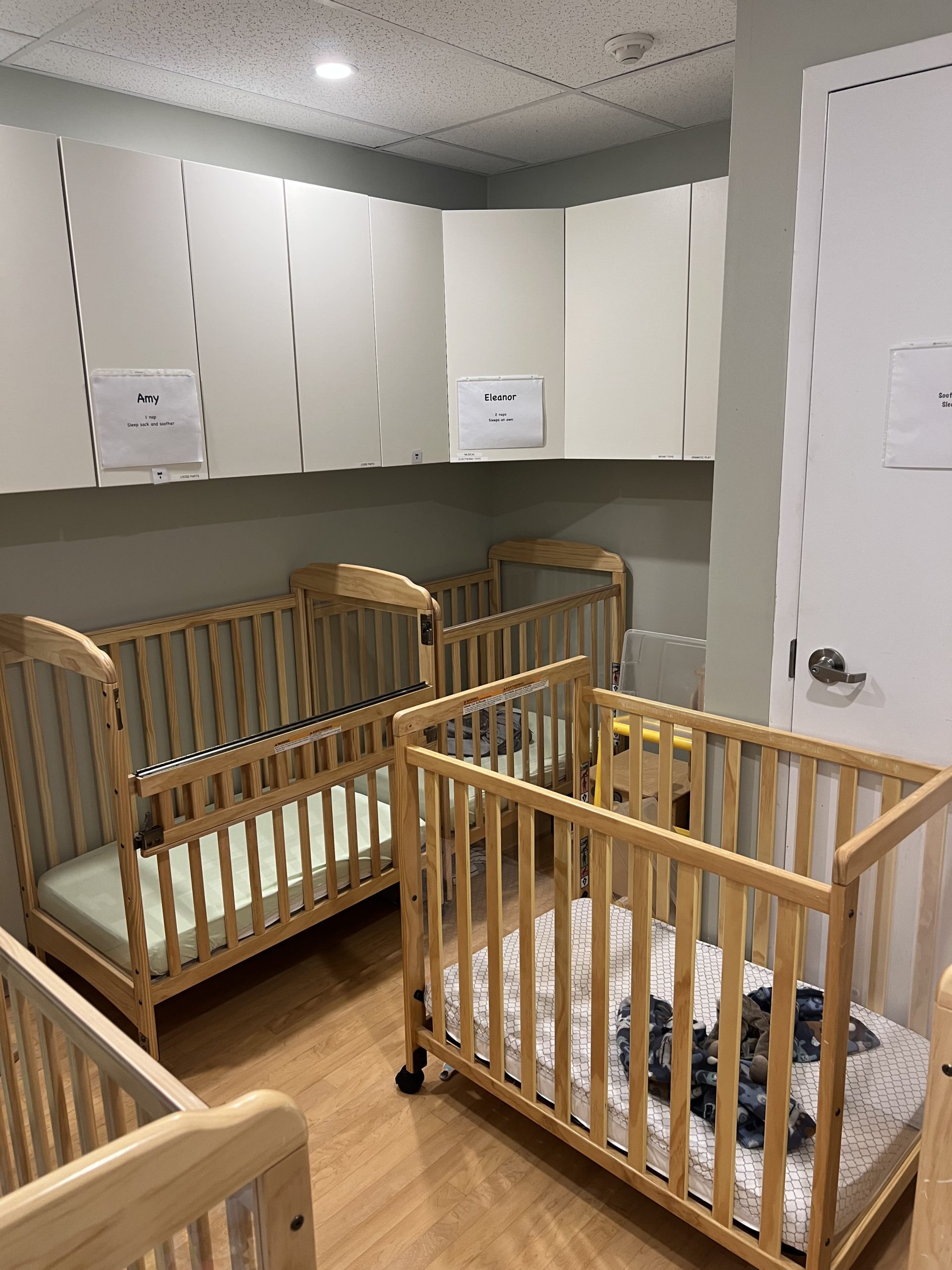 Sleep room with wooden cribs and white storage cabinets